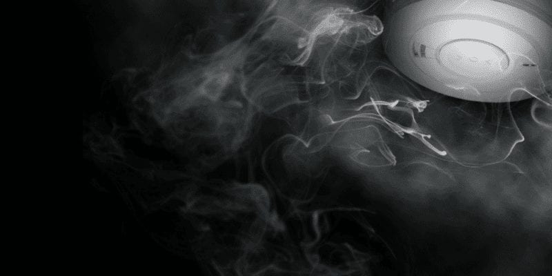 dark background image showing smoke rising to Aico smoke alarm on ceiling